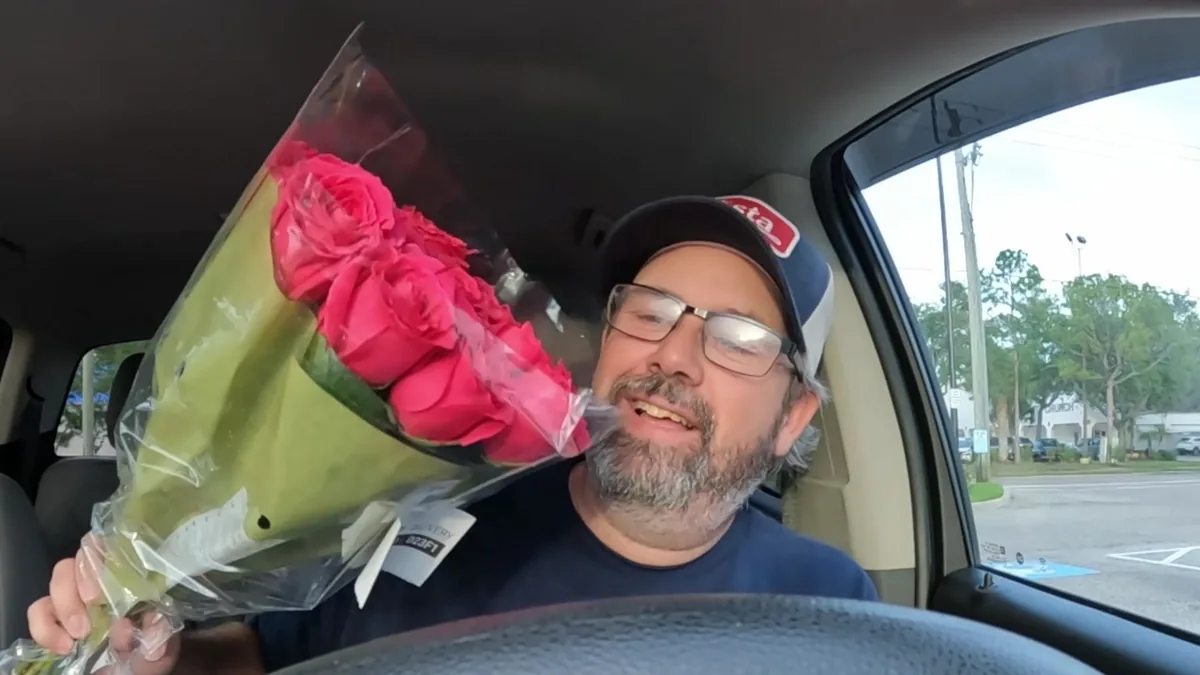 Derek holding a bouquet of pink roses during a delivery shift