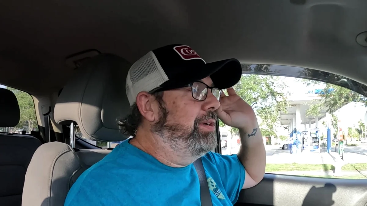 Derek sitting in his truck with his hand against his temple during a difficult delivery shift